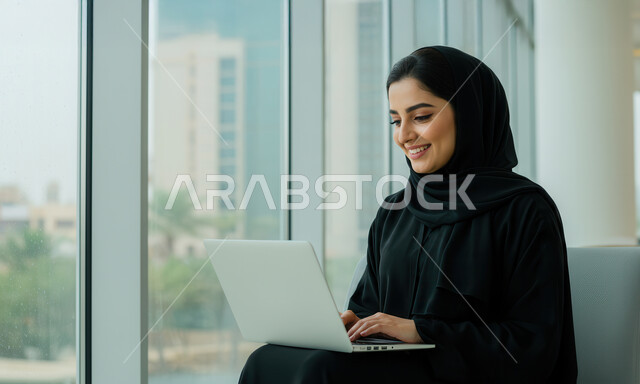  مهن ووظائف نسائية مكتبية سعودية، ادارة وانجاز المهام باستخدام جهاز تقني حديث ومتطور, إمرأة عربية خليجية سعودية مبتسمة ترتدي الحجاب والعباءة تعمل على الحاسوب المحمول في مقر الشركة, ايماءات وتعابير السرور والسعادة