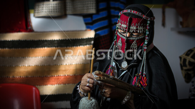 Traditional folk industries, Saudi handicrafts, ancient folk crafts and professions, the craft of making cloaks using colored threads, a Saudi Arabian Gulf woman wearing a burqa knitting and spinning fabrics and cloth