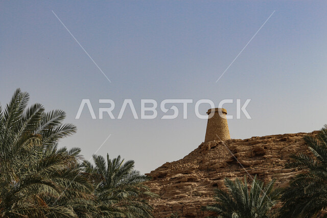 قلعة قديمة على سفوح الجبال، بيت اثري تاريخي قديم، الفن الهندسي المعماري على الطراز القديم من الحجر، الأشجار والنباتات الخضراء على سفوح الجبال في المملكة العربية السعودية، معلم تراثي على القمم والمرتفعات الجبلية