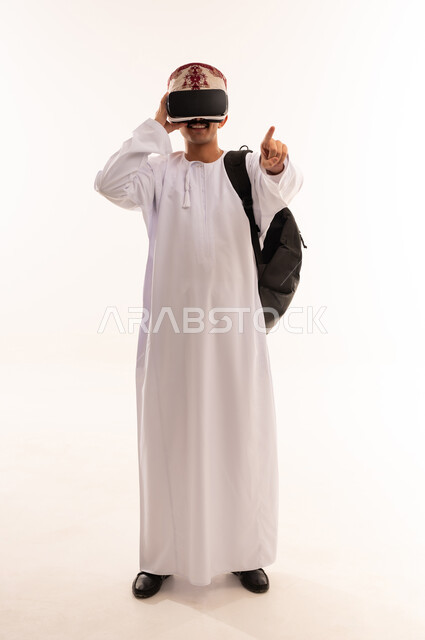 رفع اليد بإيماءات الاندماج ومحاكاة العالم الخيالي، استخدام التقنيات والتكنولوجيا المتطورة، بورتريه لشاب عربي خليجي عماني يرتدي الدشداشة والكمه العمانية يضع نظارة في آر، مشاهدة أفلام الواقع الافتراضي، قضاء أوقات الفراغ بشكل ممتع، الجسم بالطول الكامل، خلفية بيضاء
