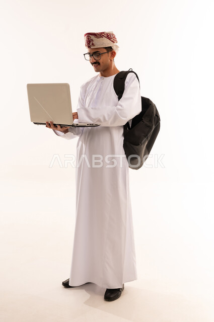 التعليم عن بعد عن طريق الانترنت، المناهج والمواد التعليمية في عمان , بورترية لشاب عربي خليجي عماني يرتدي الدشداشة و الكمه و الحقيبه  يقوم بمتابعة الدراسة عبر الحاسب، استخدام الأجهزة التقنية الحديثة لحضور المحاضرات الجامعية، الجسم بالطول الكامل، خلفية بيضاء