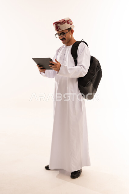 University education in Oman, gestures indicating thinking and confusion, taking notes and writing reports and scientific research, portrait of an Arab university student wearing traditional dress, holding a stack of papers in his hand and a bag on his back, reviewing daily lessons, full body, white background