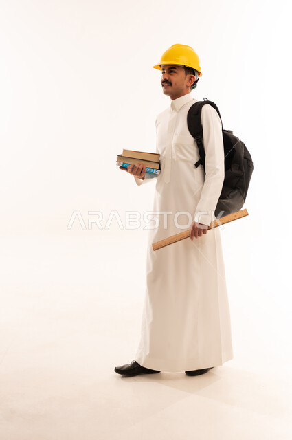 مهن ووظائف هندسية، التعليم في المملكة العربية السعودية، إدارة المشاريع الهندسية، بورتريه من الجانب لطالب جامعي يرتدي الزي الخليجي السعودي والخوذة يحمل بيده كتب ومعدات الهندسة و يقوم بالنظر الى شيء ما، الجسم بالطول الكامل، خلفية بيضاء