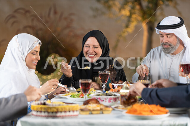 اسلاميات وعبادات رمضانية، حسن الضيافه والإستقبال، مائدة طعام مليئة بأصناف من المأكولات والمقبلات الشهية، الأجواء الرمضانية العائلية السعيدة، الاحتفال بقدوم شهر رمضان المبارك، عائله عربية خليجيه اماراتية  تقوم بتناول الطعام