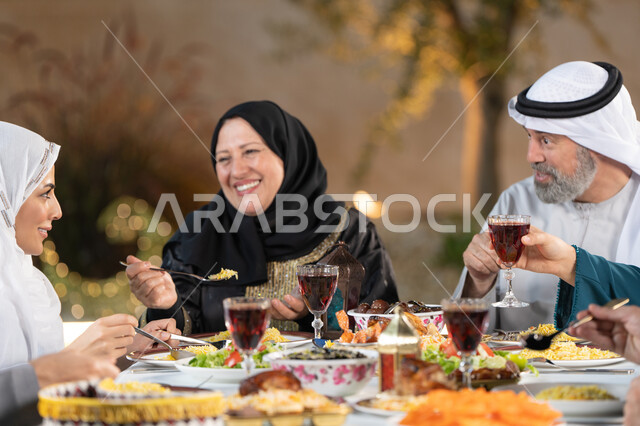 تبادل الأحاديث والنقاشات، مائدة طعام مليئة بأصناف من المأكولات والمقبلات الشهية، الأجواء الرمضانية العائلية السعيدة، الاحتفال بقدوم شهر رمضان المبارك، عائله عربية خليجيه اماراتية تقوم بتناول الطعام، اسلاميات وعبادات رمضانية