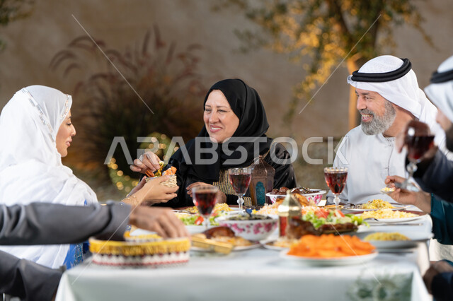 مائدة إفطار مليئة بأصناف المأكولات الشهية، أجواء وعبادات دينية إسلامية، فطور رمضاني عائلي, عائلة عربية خليجية إماراتية تجلس على سفرة الطعام, حلول موعد الإفطار عند اذان المغرب، تبادل الأحاديث والنقاشات بإيماءات السعادة والسرور