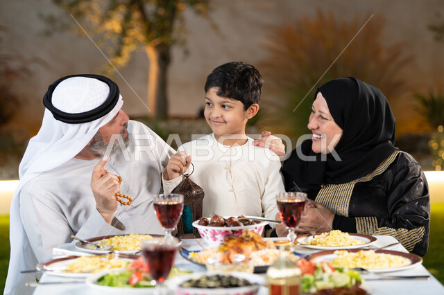 تناول الافطار الرمضاني عند أذان المغرب، عائلة عربية خليجيه إماراتيه تستعد لتناول الطعام ، سفرة مليئة بأصناف من المأكولات والمقبلات الشهية,  اسلاميات وعبادات رمضانية، تبادل الأحاديث والنقاشات بإيماءات السعادة والسرور