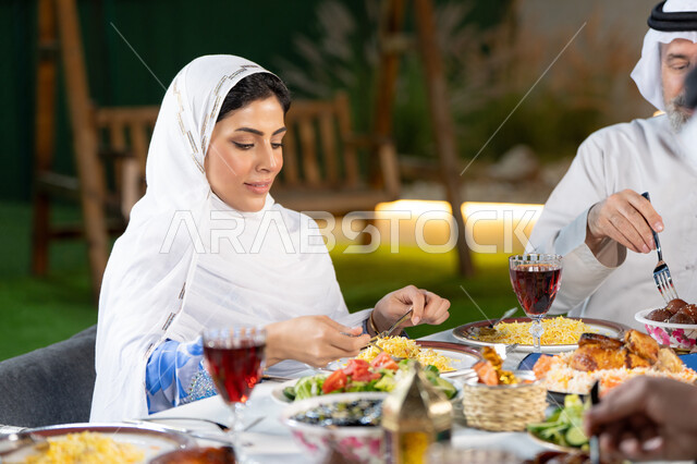 Banquets and feasts on Islamic holidays and occasions, the atmosphere of the holy month of Ramadan, delicious oriental Arab dishes and dishes, an Emirati Gulf Arab woman eating, a table of delicious traditional popular foods