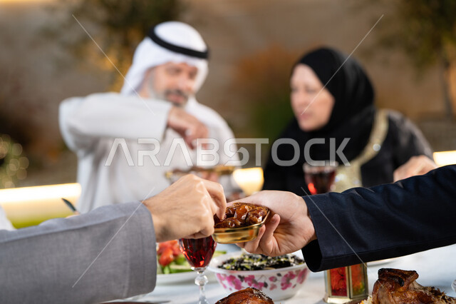 الأجواء الرمضانية الروحانية، حلى رمضاني شهير، صورة مقربة ليد رجل عربي يحمل بيده صحن مليء بحلوى اللقيمات الشهية، حسن الضيافة والاستقبال في شهر رمضان المبارك، عائله عربية خليجيه اماراتية تجتمع حول الطعام