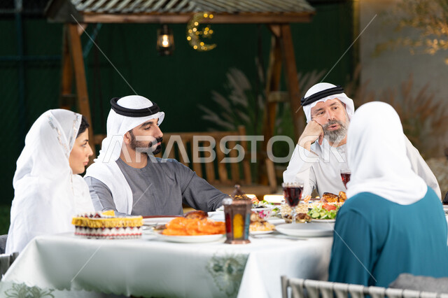 اجتماع العائلة حول مائدة الطعام،أداء فريضة الصيام، أجواء دينية رمضانية، أسرة عربية خليجية اماراتية تقوم بتبادل الأحاديث والنقاشات بإيماءات السعادة والسرور، سفرة مليئة باصناف من المأكولات الشرقية الشهية
