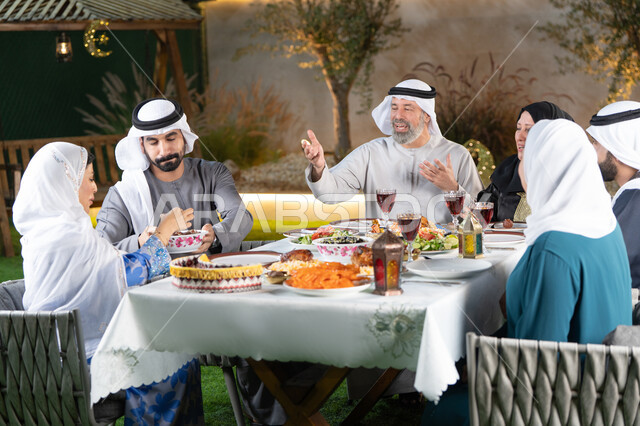 The spiritual atmosphere of Ramadan, gestures of happiness and joy at the arrival of the holy month of Ramadan, serving food to the family, a family gathering at the iftar table, a Gulf man serving a plate of dates to his wife, Islamic and religious occasions.