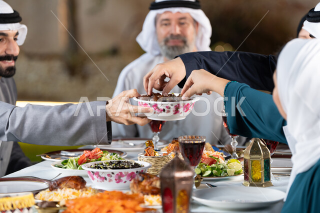 مائدة إفطار مليئة بالأصناف والمأكولات الشهية، قضاء أوقات ممتعة مع العائلة في الهواء الطلق، عائلة عربية خليجية إماراتية تقوم بتناول التمر بايماءات السعادة و السرور، الشهر الكريم والأجواء الرمضانية الروحانية