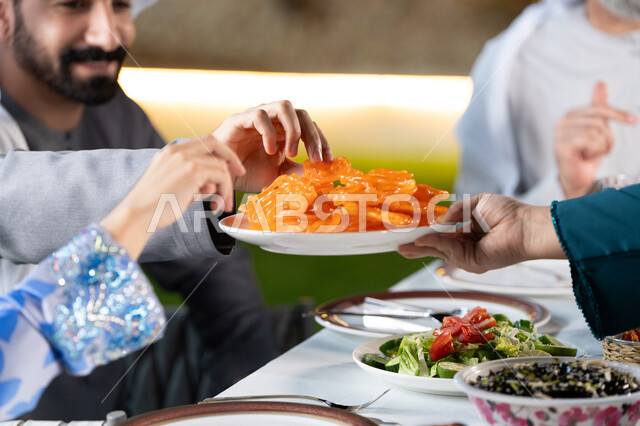 كسر الصيام عند سماع أذان المغرب، قضاء أوقات ممتعه مع العائله في الخارج، صورة مقربة ليد عائله عربيه خليجيه اماراتية تقوم بتناول الحلويات الشرقية بايماءات السعادة و السرور، مائده إفطار مليئه بالأصناف والمأكولات الشهية، الأجواء الرمضانية الروحانية