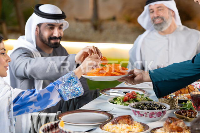 قضاء أوقات ممتعه مع العائله في الخارج، صورة مقربة لعائله عربيه خليجيه اماراتية تقوم بتناول الحلويات الشرقية بايماءات السعادة و السرور، كسر الصيام عند سماع أذان المغرب، مائده إفطار مليئه بالأصناف والمأكولات الشهية، الأجواء الرمضانية الروحانية