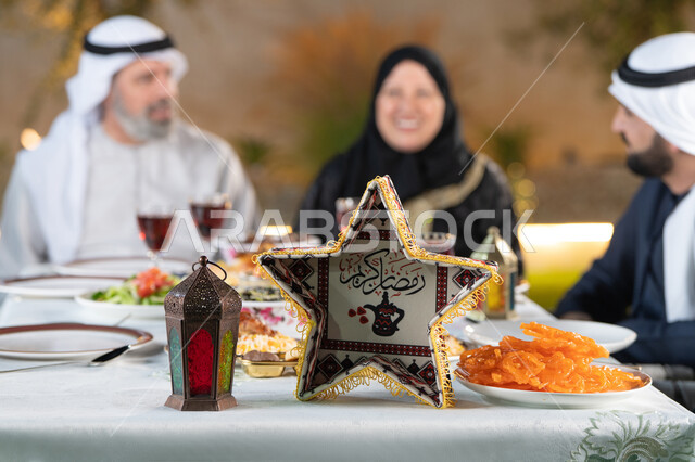 ديكور وأجواء رمضانية، مائده طعام مليئه بأصناف المأكولات و المقبلات الشهية، نقاش وحوار عائلي، تجمع أسرة عربية خليجية اماراتية حول سفرة الإفطار في شهر رمضان المبارك، ايماءات السعادة والسرور