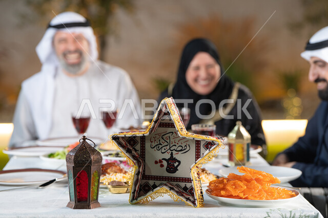 مائده طعام مليئه بأصناف المأكولات و المقبلات الشهية، ديكور وأجواء رمضانية، نقاش وحوار عائلي، تجمع أسرة عربية خليجية اماراتية حول سفرة الإفطار في شهر رمضان المبارك، ايماءات السعادة والسرور