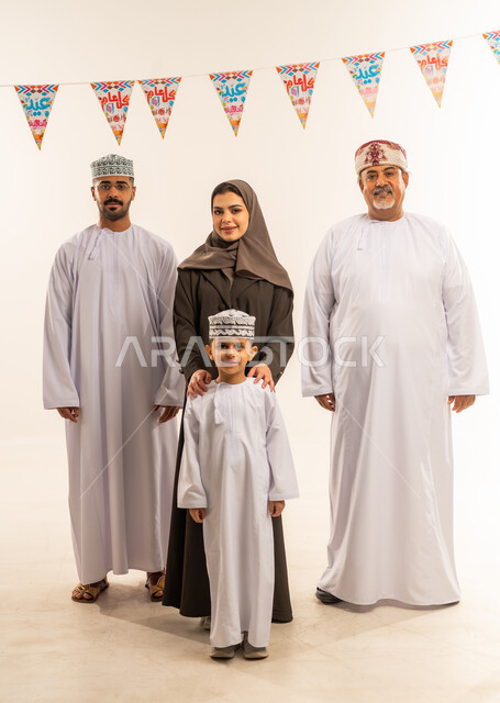 تقديم التهنئات فى العيد ,النظر االكاميرا بايماءات السعادة ، أجواء البهجة والسعادة في العيد, بورتريه لعائلة عربية خليجية عمانية تحتفل بالأعياد الاسلامية, الديكورات والزينة الرمضانية ، اجواء رمضانية روحانية ,الجسم بالطول الكامل ، خلفية بيضاء .