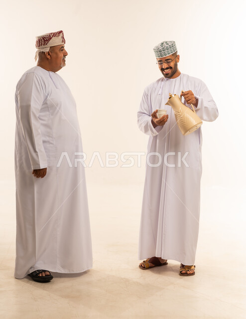 تقديم الضيافة العربية ،  مناسبات واعياد اسلاميه, زيارات وتجمعات عائليه, تعبيرات الفرحة و السرور و السعادة بالاحتفاليات, رجل عربي عماني خليجي يقدم الضيافة لوالده ، الاحتفال بقدوم العيد ، صورة الجسم بالطول الكامل ، خلفية بيضاء .