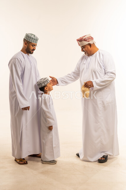 السلام و التهنئة بقدوم العيد, أجواء البهجة والسعادة والاحتفال, إظهار مشاعر المودة والمحبة العائلية, ديكورات وزينة رمضانية ، بورتريه لعائلة عربية خليجية عمانية تحتفل بالأعياد الاسلامية وتتبادل المعايدات, تقديم العيش و الحلوى فى العيد ، خلفية بيضاء.