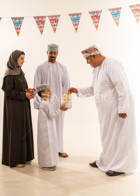 المعايدات والتهنئات وطقوس المناسبات الاسلامية، التهنئة بقدوم العيد, ديكورات وزينة رمضانية ، أجواء البهجة والسعادة والاحتفال, إظهار مشاعر المودة والمحبة العائلية,  بورتريه لعائلة عربية خليجية عمانية تحتفل بالأعياد الاسلامية ، تقديم العيش والحلوى فى العيد ، خلفية بيضاء.