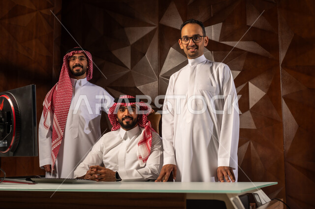 النظر الى الكاميرا بتعابير وايماءات السرور والسعادة, مهنة ووظيفة ادارية سعودية, شرح خطط و استراتيجيات المهام المطلوبة, التعارف وبناء العلاقات الاجتماعية, مجموعة رجال عرب خليجيين سعوديين يرتدون الزي التقليدي في مقر الشركة