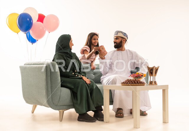 الزيارات العائلية وتبادل التهنئات والمعايدات بين أفراد الأسرة بإيماءات الفرح والسرور ، توثيق اللحطات التذكارية ، تقديم الحلويات والضيافة الشعبية, بورتريه لعائلة عربية خليجية عمانية تحتفل بالعيد السعيد, طقوس الأعياد والمناسبات الاسلامية في سلطنة عمان ، خلفية بيضاء .