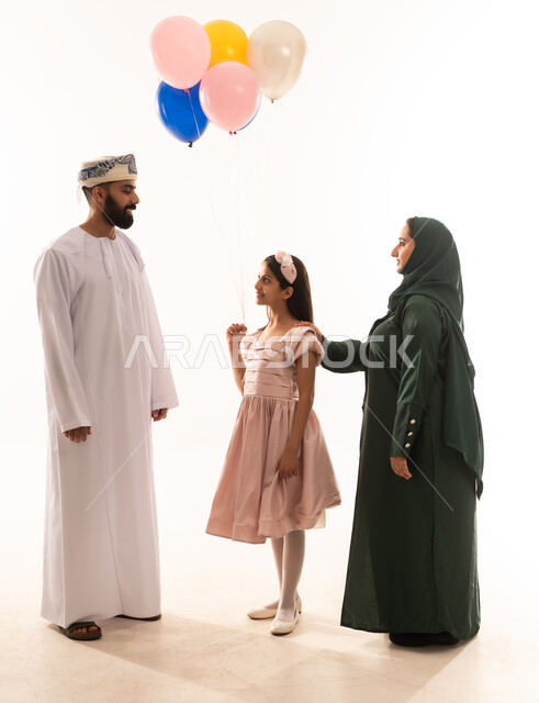 المعايدات والتهنئات وطقوس المناسبات الاسلامية في سلطنة عمان، مفهوم الكرم وتقديم الضيافة العربية، ارتداء الأزياء العمانية التقليدية، توزيع الحلويات الشعبية في الأعياد، جو البهجة والفرح والزينة، بورتريه لعائلة عربية خليجية عمانية تحتفل بالعيد المبارك، خلفية بيضاء .