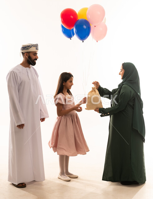طقوس الاحتفالات والمناسبات السعيدة في سلطنة عمان، مفهوم الكرم وتقديم الضيافة العربية، ارتداء الأزياء العمانية التقليدية، توزيع الحلويات الشعبية في الأعياد، جو البهجة والفرح والزينة، بورتريه لعائلة عربية خليجية عمانية تحتفل بالعيد المبارك، خلفية بيضاء .