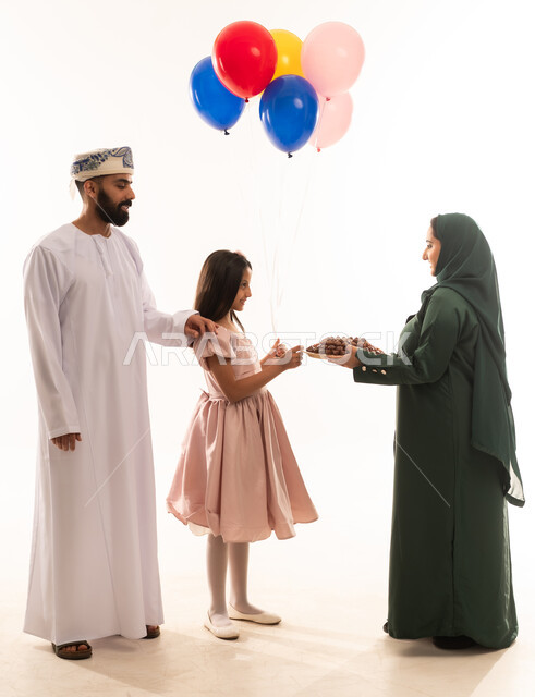 مفهوم الكرم وتقديم الضيافة العربية، ارتداء الأزياء العمانية التقليدية، توزيع الحلويات الشعبية في الأعياد، جو البهجة والفرح والزينة، طقوس الاحتفالات والمناسبات السعيدة في سلطنة عمان، بورتريه لعائلة عربية خليجية عمانية تحتفل بالعيد المبارك، خلفية بيضاء .