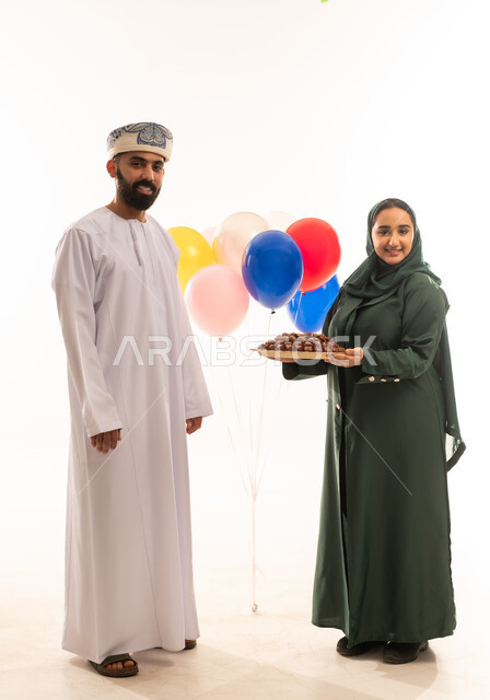 Iftar meal in Ramadan, a meal with high nutritional value, a portrait of an Omani Gulf Arab woman wearing an abaya and hijab offering healthy dates to her husband, a local national agricultural product, a delicious Ramadan hospitality, the concept of respecting and appreciating the husband, celebrating the arrival of the month of goodness, a white background.