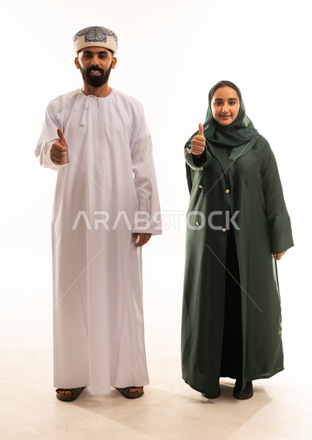 ايماءات الجودة والامتياز ، قضاء اوقات عائلية ممتعة ومسلية، اجواء مليئة بالحب ، بورتريه لرجل عربي خليجي عماني يرتدي الدشداشة والكمة يقف مع زوجته بتعابير السعادة والسرور، تعزيز العلاقات الاجتماعية، الجسم بالطول الكامل، خلفية بيضاء .