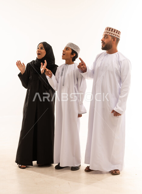 النظر الى مكان معين، التوجه والإشارة الى شيء ما، رعاية لآباء بالأبناء والاهتمام بهم، مفهوم لغة الجسد، بورتريه لعائلة عربية خليجية عمانية يشيروا بإصبع السبابة الى الأعلى دلالة على موقع محدد، خلفية بيضاء .