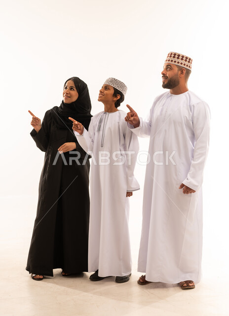 التوجه والإشارة الى شيء ما، النظر الى مكان معين، رعاية لآباء بالأبناء والاهتمام بهم، مفهوم لغة الجسد، بورتريه لعائلة عربية خليجية عمانية يشيروا بإصبع السبابة الى الأعلى دلالة على موقع محدد، خلفية بيضاء .