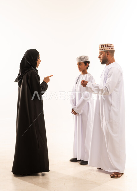 ايماءات الحزم والجديه في الحوار، مفهوم تبادل الأحاديث والدردشات مع الأهل، مشاعر الألفه والمحبه بين أفراد العائله، بورتريه لعائلة عربية خليجية عمانية ترتدي الملابس العمانية التقليدية تقوم بالنقاش حول موضوع معين، الجسم بالطول الكامل، خلفية بيضاء .