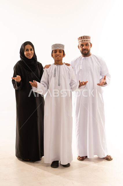 الشعور بالحيرة والجهل بأمر ما، التردد وانعدام المعرفة بخصوص شيء معين، الاهتمام بالأبناء ورعايتهم، بورتريه لعائلة عربية خليجية عمانية يرتدي الملابس العمانية التقليدية تنظرالى الكاميرا ، تعزيز العلاقات الاجتماعية، الجسم بالطول الكامل، خلفية بيضاء .