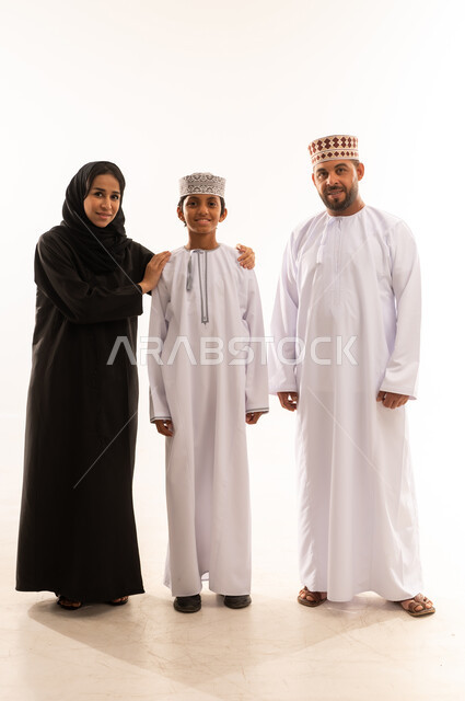 قضاء اوقات عائلية ممتعة ومسلية، الاهتمام بالأبناء ورعايتهم، بورتريه لعائلة عربية خليجية عمانية يرتدي الملابس العمانية التقليدية تقف بايماءات السعادة والسرور، تعزيز العلاقات الاجتماعية، الجسم بالطول الكامل، خلفية بيضاء .