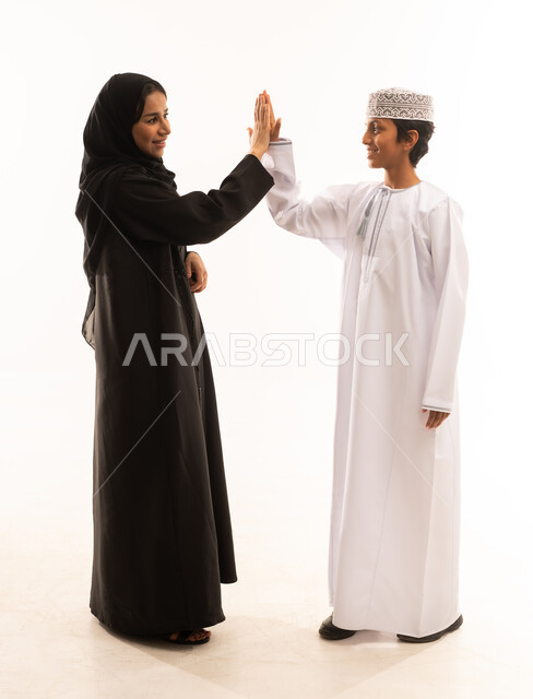 Agreement and handshake, wearing traditional Omani clothes on Islamic holidays, gestures of love and affection for children, a mother's love for her children, motherhood and family bonding, portrait of a mother and her son, two Gulf Arab Omanis wearing Omani clothes, looking at each other with gestures of happiness, white background.