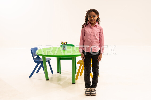 Schools and kindergartens in Saudi Arabia, preparing for the start of a new school year, gestures and expressions of joy and happiness for the start of the school term, portrait of a Saudi Arabian Gulf girl wearing casual clothes, standing straight and looking at the camera, full body length, white background