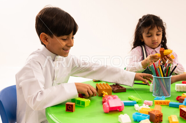 الجلسات والحصص التعليمية في الروضات السعودية، بورتريه لطلاب عرب خليجيين سعوديين يقومون باللعب في المكعبات الملونة، تنمية القدرات العقلية والذهنية، القيام بالمهارات و الأنشطة المسلية الممتعة، تنيمة المهارات الفنية بالتشكيل، خلفية بيضاء