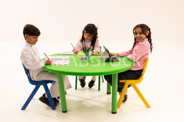 Learning concentration and innovation skills through the tablet, an entertaining and fun activity, enhancing students' artistic creative talents, a portrait of a Saudi Arabian Gulf student using a tablet with her friends, drawing, coloring, and using modern technical devices, white background