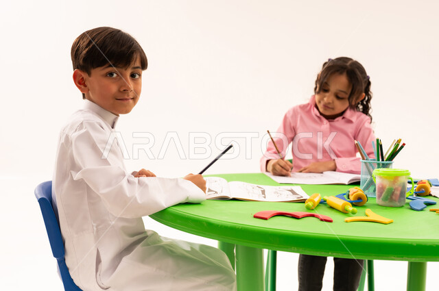 تنيمة المهارات الفنية بالرسم والتلوين، الجلسات والحصص التعليمية في الروضات السعودية، بورتريه لطلاب عرب خليجيين سعوديين يقومون بتلوين الرسومات بايماءات الاندماج، القيام بالمهارات و الأنشطة المختلفة لتنمية القدرات العقلية والذهنية، خلفية بيضاء