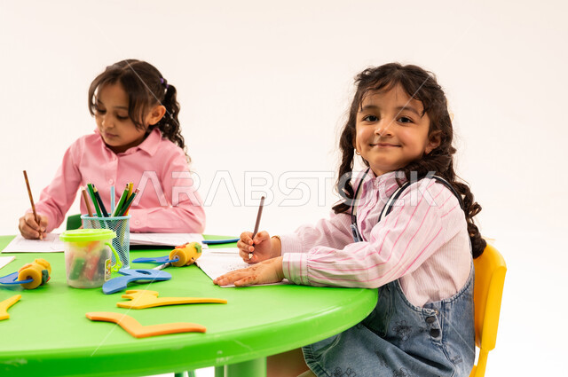 تقوية المهارات الفنية بالرسم والتلوين، الجلسات والحصص التعليمية في الروضات السعودية، بورتريه لطلاب عرب خليجيين سعوديين يقومون بتلوين الرسومات بايماءات الاندماج، القيام بالمهارات و الأنشطة المختلفة لتنمية القدرات العقلية والذهنية، خلفية بيضاء