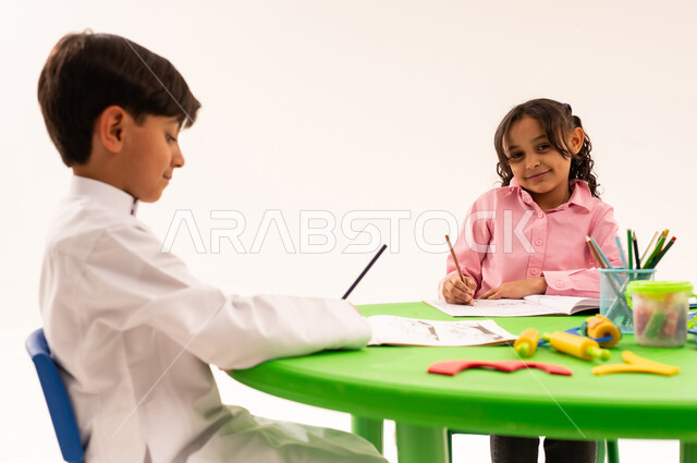 Strengthening artistic skills through drawing and coloring, educational sessions and classes in Saudi kindergartens, portrait of Saudi Arabian Gulf students coloring drawings with integration gestures, performing various skills and activities to develop mental and intellectual abilities, white background