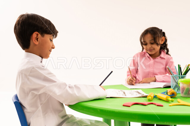 تعزيز المهارات الفنية بالرسم والتلوين، الجلسات والحصص التعليمية في الروضات السعودية، بورتريه لطلاب عرب خليجيين سعوديين يقومون بتلوين الرسومات بايماءات الاندماج، القيام بالمهارات و الأنشطة المختلفة لتنمية القدرات العقلية والذهنية، خلفية بيضاء
