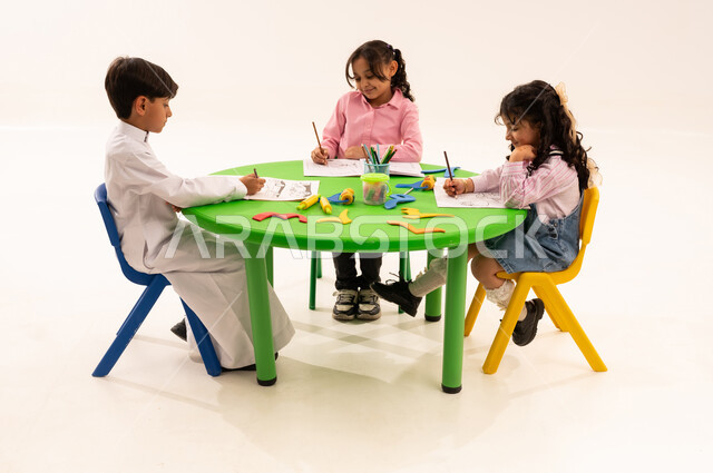 Developing artistic skills through drawing and coloring, educational sessions and classes in Saudi kindergartens, a portrait of Saudi Arabian Gulf students coloring drawings with integration gestures, performing various skills and activities to develop mental and intellectual abilities, white background