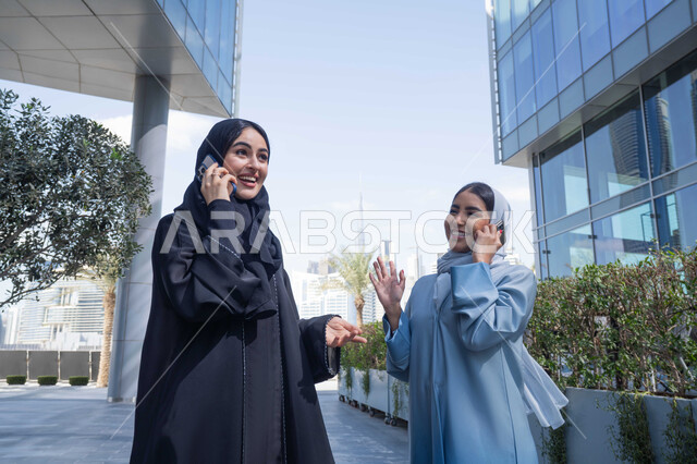 الإستمتاع مع الأصدقاء, التجول في إحدى المناطق العامة ، التواصل مع العائلة عبر الجوال ، اجراء المكالمات الهاتفية ، سيدتان اماراتيان تقومان بالتنزه في وقت العطلة ، صديقتان عربيتان خليجيتان سعوديتان مبتسمتان تسيران معاً في نزهة ممتعة لإحدى الأماكن الترفيهية ، علاقات اجتماعية ، قضاء أوقات ممتعة .