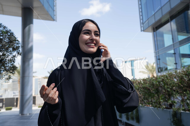 ايماءات السعادة لسماع الاخبار المبهجة ، برامج وتطبيقات الجوال المتنوعة ، الاطمئنان على الأصدقاء، تبادل الاحاديث والاخبار بين العائلة، امرأة اماراتية تقوم بإستخدام الأجهزة التقنية الحديثة، شابة عربية خليجية سعودية مبتسمة تمسك بيدها جهاز الهاتف المحمول تقوم بإجراء مكالمة هاتفية  .