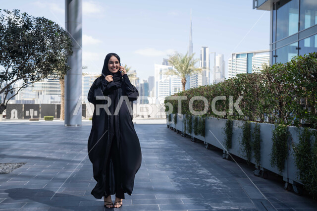 الاطمئنان على الأصدقاء، تبادل الاحاديث والاخبار بين العائلة، امرأة اماراتية تقوم بإستخدام الأجهزة التقنية الحديثة، شابة عربية خليجية سعودية مبتسمة تمسك بيدها جهاز الهاتف المحمول تقوم بإجراء مكالمة هاتفية ، برامج وتطبيقات الجوال المتنوعة .