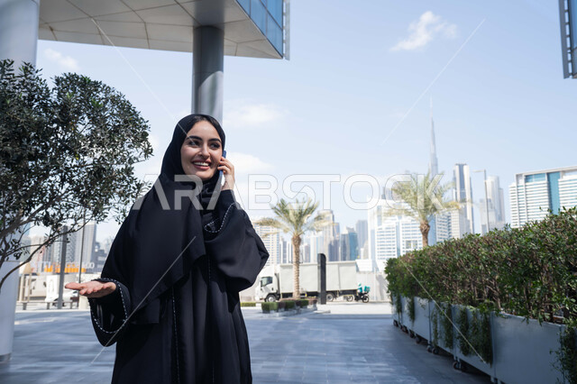 تبادل الاحاديث والاخبار بين العائلة، الاطمئنان على الأصدقاء، امرأة اماراتية تقوم بإستخدام الأجهزة التقنية الحديثة، شابة عربية خليجية سعودية مبتسمة تمسك بيدها جهاز الهاتف المحمول تقوم بإجراء مكالمة هاتفية ، برامج وتطبيقات الجوال المتنوعة .