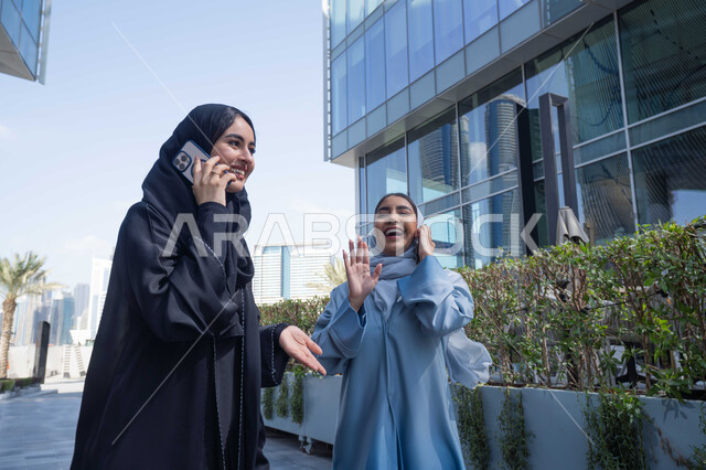 ايماءات السرور والسعادة ، قضاء أوقات ممتعة مع الاصدقاء ، التواصل مع العائلة عبر الجوال ، اجراء المكالمات الهاتفية ، صورة مقربة لسيدتان اماراتيان تقومان بالتنزه في وقت العطلة ، الإستمتاع مع الأصدقاء, التجول في إحدى المناطق العامة ، صديقتان عربيتان خليجيتان سعوديتان مبتسمتان تسيران معاً في نزهة ممتعة لإحدى الأماكن الترفيهية ، علاقات اجتماعية .
